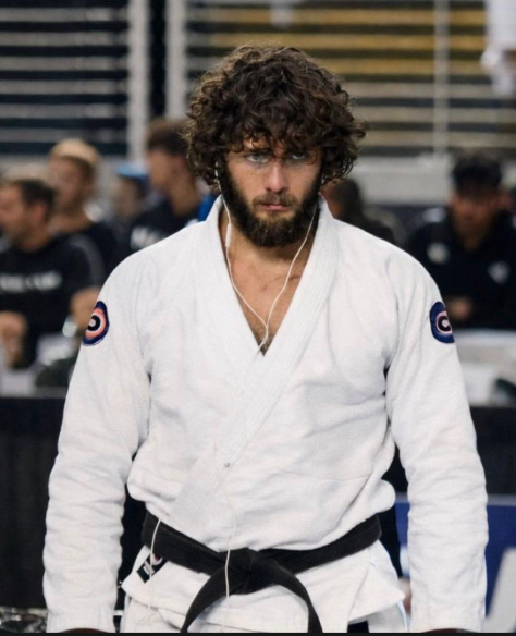 Roberto Jimenez, black belt professor, in a white gi and black belt at a competition venue