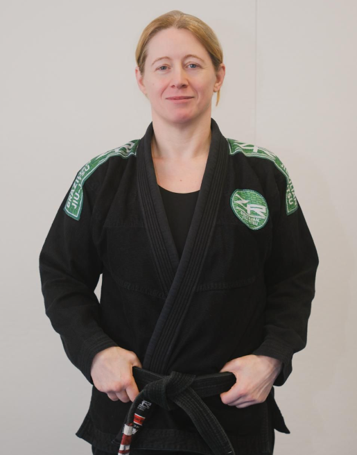 Sarah Merriner, black belt professor, in a black gi tying her black belt